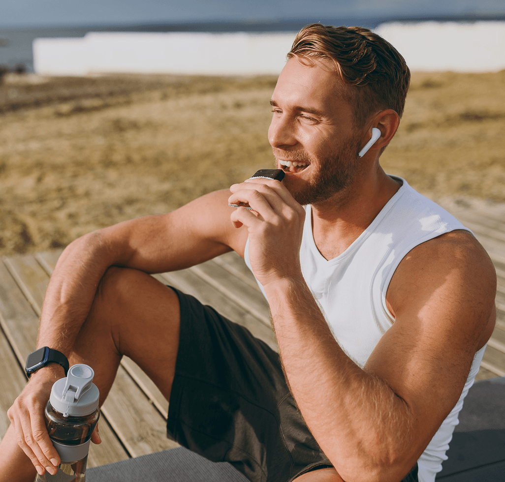 Man eats a snack bar after a workout by the beach